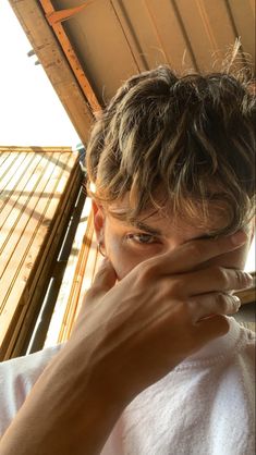 a man covering his face with his hands while sitting in front of a wooden structure