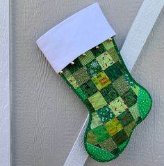 a christmas stocking hanging on the side of a house with white trim and green patchwork