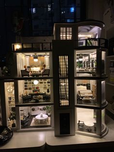 a doll house is lit up at night with lights on and furniture in the room