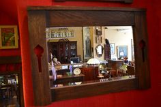 a mirror is hanging on the wall in a room that has red walls and furniture