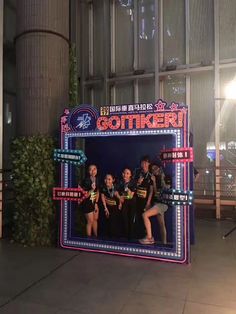 a group of young people standing in front of a photo booth at an amusement park