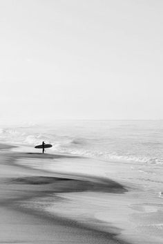 a person with a surfboard walking on the beach