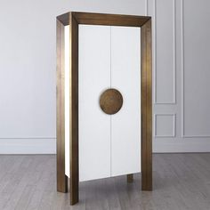 a white cabinet with a wooden door and a round hole in the middle, on a wood floor