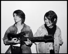 two people standing next to each other holding guitars