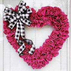 a heart shaped wreath with black and white checkered ribbon hanging on a window sill