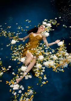 a woman floating in the water surrounded by white and yellow flowers with her legs spread out