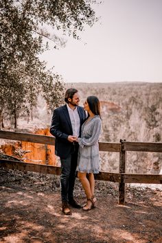 a man and woman standing next to each other near a fence