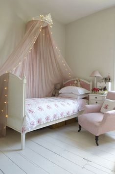 a pink canopy bed in a girls'bedroom with white furniture and lights on the ceiling