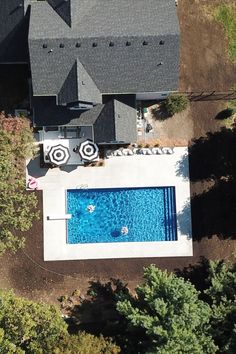 an aerial view of a house with a swimming pool in the yard and trees surrounding it