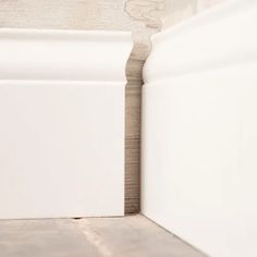 the corner of a room with white walls and wood flooring on one side, looking like it has been painted