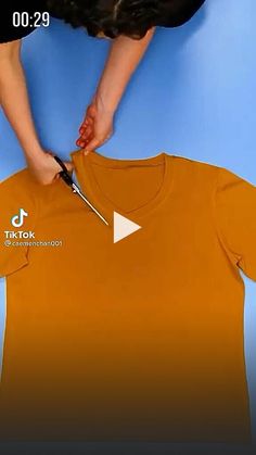 a person cutting an orange t - shirt with scissors