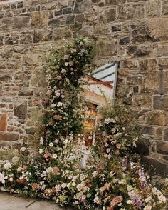 an old brick building with flowers growing on it's side and a sign in the background