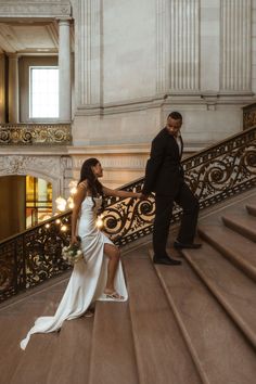 a bride and groom walking down the stairs at their wedding reception in an old building