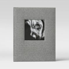 a black and white photo of a dog's face on a gray linen album