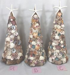 three small christmas trees with seashells on them