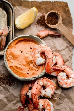 a bowl of sauce with shrimp next to it