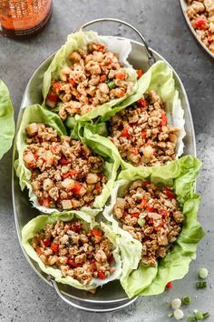 lettuce wraps filled with meat and vegetables on a plate next to some dipping sauce