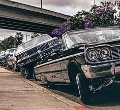 an old car is parked on the side of the road with other cars behind it