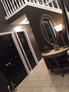 a bedroom with a bed, mirror and stairs in the background is shown from across the room