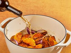 a person pouring wine into a pot filled with food