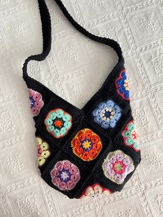 a black crocheted purse with multicolored flowers on the front and sides