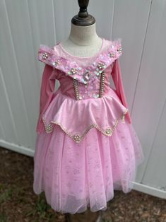 Step into a world of fairy tale magic with our Enchanted Rose Princess Dress. This beautiful pink dress features a shimmering bodice adorned with sparkling sequins, intricate floral embroidery, and delicate jewel accents. The layered tulle skirt, decorated with glittering star patterns, adds a touch of whimsy and elegance. Long sleeves provide extra warmth and comfort, making this dress perfect for cooler days. Ideal for themed parties, dress-up play, or any special occasion, this dress will mak Fairytale Tulle Dress For Pageant, Fairytale Tulle Pageant Dress, Fairytale Tulle Dress For Pageants, Pink Long Sleeve Ball Gown For Prom, Pink Princess Ball Gown Dress, Pink Princess Style Ball Gown Dress, Pink Princess Ball Gown For Fancy Dress, Pink Fitted Fairy Dress For Fancy Dress, Pink Princess Style Ball Gown For Fancy Dress