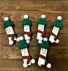 four snowmen made out of popsicle sticks with hats and scarfs on them