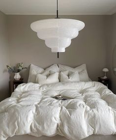 a bed with white linens and pillows in a room that looks like it has been made