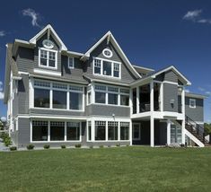 a large gray house sitting on top of a lush green field