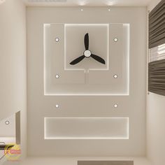 a clock mounted to the wall in a room with white walls and ceiling fan on it's side