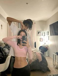 a man and woman taking a selfie in a bedroom