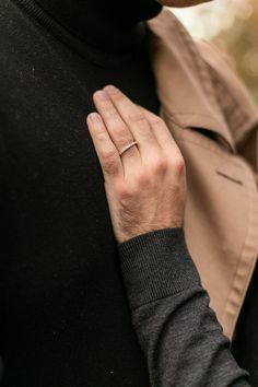 a woman wearing a black turtle neck sweater and a ring on her left hand,