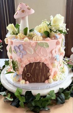 a pink cake decorated with flowers and a mushroom on top is sitting on a table