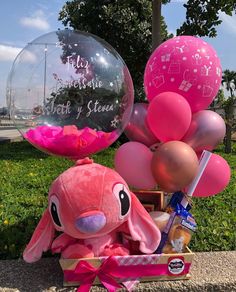 a pink stuffed animal sitting next to some balloons