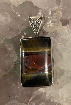 "3stones intarsia (tiger's eye/ Boulder opal/tiger's eye) with silver between. Stone 1 1/4\" tall. 1 7/8\" tall total. Back of pendant has 2 pine trees carved into it and a moon etched in." Brown Polished Agate Jewelry, Unique Brown Jewelry With Inlay, Artisan Brown Inlay Jewelry, Brown Natural Stones Jewelry For Collectors, Collectible Brown Jewelry With Natural Stones, Unique Brown Cabochon Jewelry, Brown Artisan Jewelry With Cabochon, Artisan Brown Jewelry With Cabochon, Artisan Brown Rectangular Jewelry