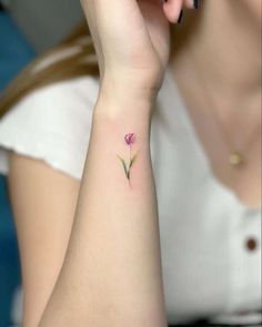 a woman with a small pink flower tattoo on her wrist