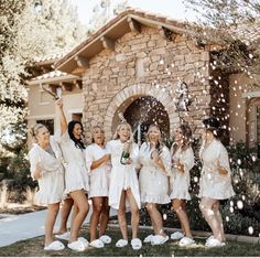 a group of women standing next to each other in front of a house with confetti