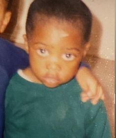 an old photo of a young boy with his arm around the shoulder and looking at the camera