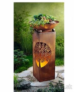 a potted plant sitting on top of a stone slab in the middle of a garden