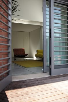 an open door leading to a living room with a green chair and yellow rug on the floor