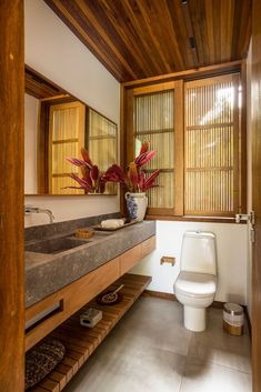 a bathroom with a toilet, sink and wooden paneled walls on the wall are bamboo shutters