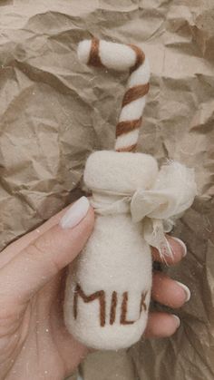 a hand holding a small glass bottle with a candy cane sticking out of it