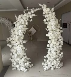 an arch made out of white flowers in a room