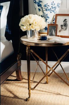 a table with flowers and pictures on it in front of a blue painted bedroom wall