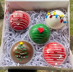 four decorated cupcakes in a box on a table