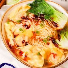 a bowl filled with noodles and vegetables on top of a table