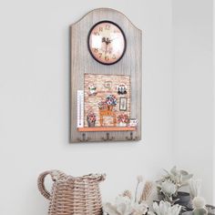 a clock mounted to the side of a wall next to a wicker basket filled with flowers