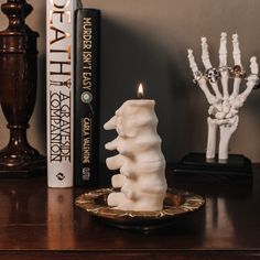 a white candle sitting on top of a wooden table next to two bookends