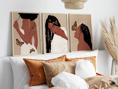 three framed art pieces on the wall above a bed with pillows and throw pillows in front of them