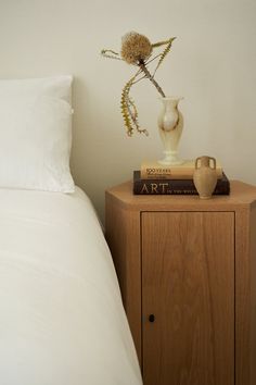 a nightstand with a book and vase on it